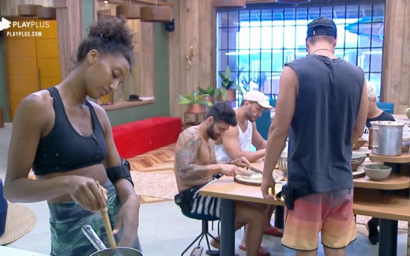 Peões cantam na cozinha, enquanto preparam o almoço da sede